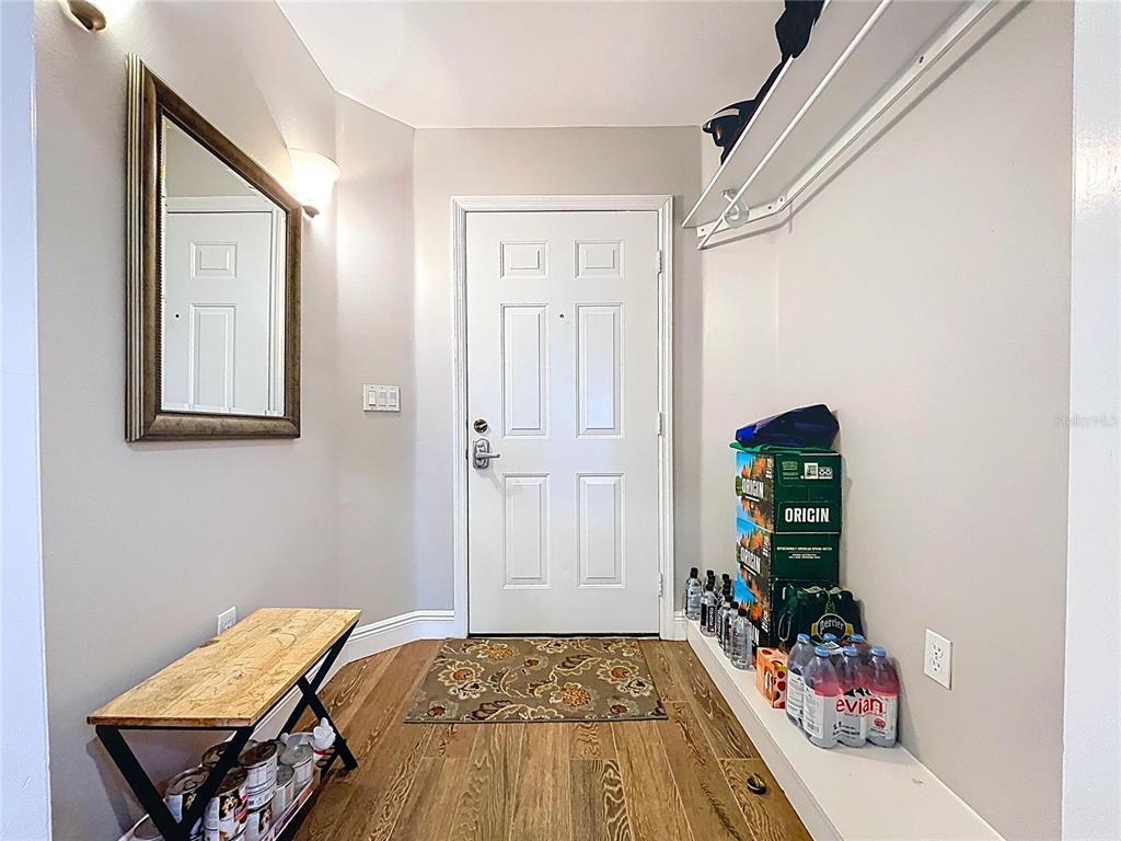 An entryway features a wooden bench, a wall mirror, and a white door — 3803 54TH DRIVE W UNIT 102, BRADENTON, FL