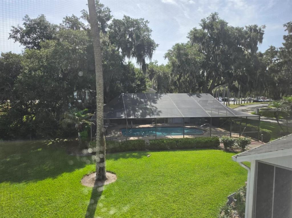 An elevated view of a backyard featuring a screened-in swimming pool and large oak trees — 416 EAGLE RIDGE DRIVE UNIT 416, DAVENPORT, FL