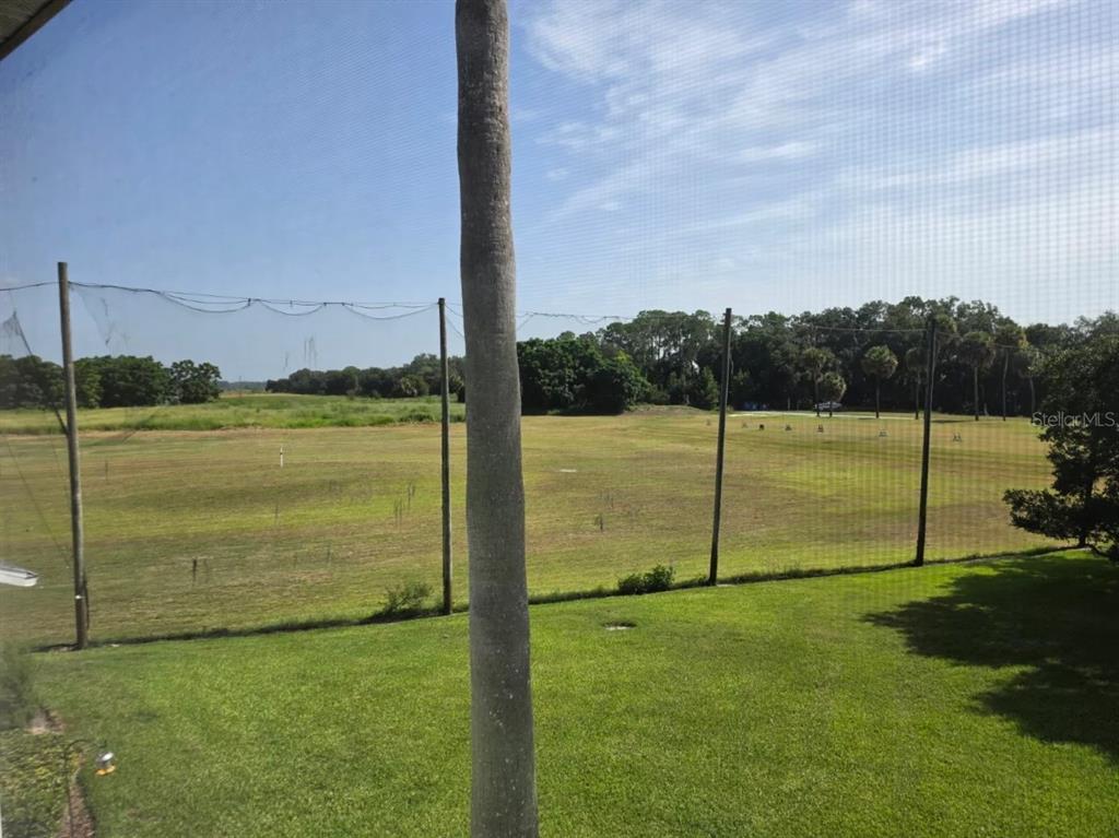 A view of a grassy field and trees from behind a screened-in patio — 416 EAGLE RIDGE DRIVE UNIT 416, DAVENPORT, FL