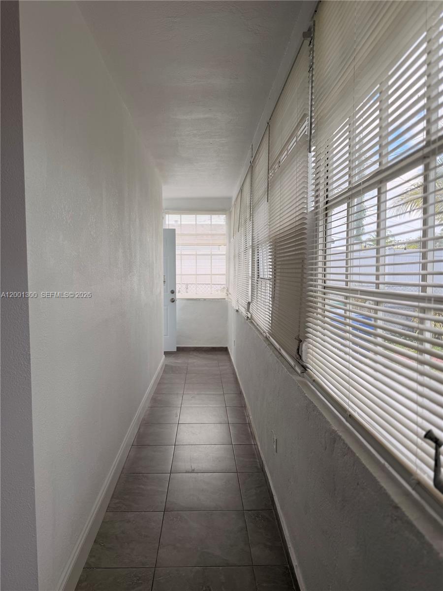 A narrow, enclosed sunroom features tiled flooring, white walls, and large windows with blinds — 6613 Evergreen Dr # B, Miramar FL 33023, MIRAMAR, FL
