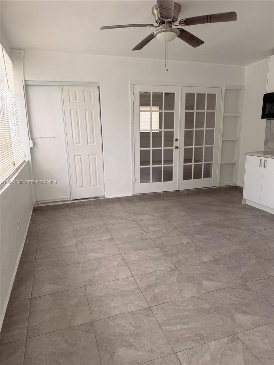 A room with gray tile flooring, a ceiling fan, a white door, and French doors — 6613 Evergreen Dr # B, Miramar FL 33023, MIRAMAR, FL