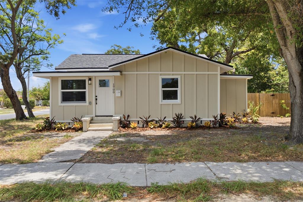 A single-story house with beige vertical siding, a white front door, and a shingled roof — 1700 SCRANTON STREET S, ST PETERSBURG, FL