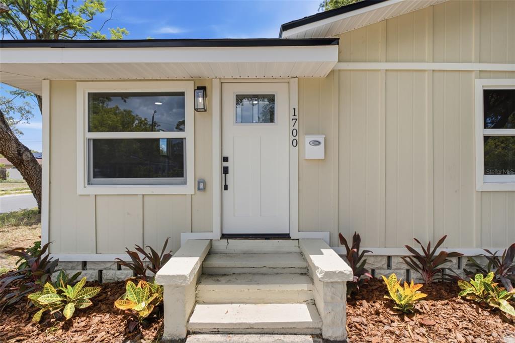 The exterior of a house features a white front door, concrete steps, and landscaping — 1700 SCRANTON STREET S, ST PETERSBURG, FL