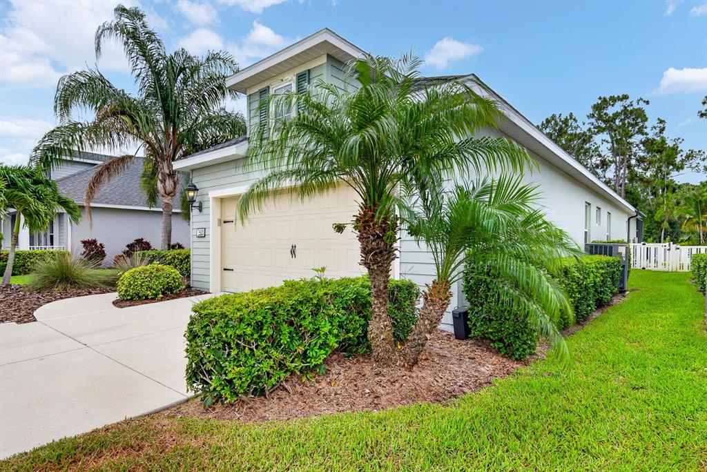A light-colored house exterior features a two-car garage, a palm tree, and manicured landscaping — 7428 RIDGELAKE CIRCLE, BRADENTON, FL