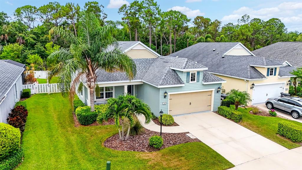 An exterior view of a light blue suburban house with a two-car garage and palm trees — 7428 RIDGELAKE CIRCLE, BRADENTON, FL