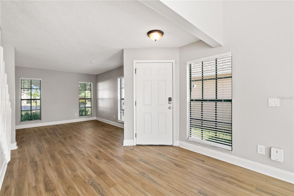 An entryway with light gray walls, wood-look flooring, a white front door, and several windows — 1931 SHEELER OAKS DRIVE, APOPKA, FL