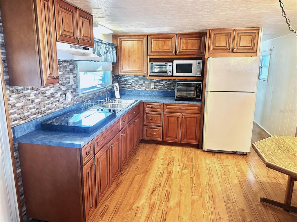 A kitchen features wood cabinets, blue laminate countertops, a white refrigerator, and wood-look flooring — 9790 66TH STREET N UNIT 330, PINELLAS PARK, FL