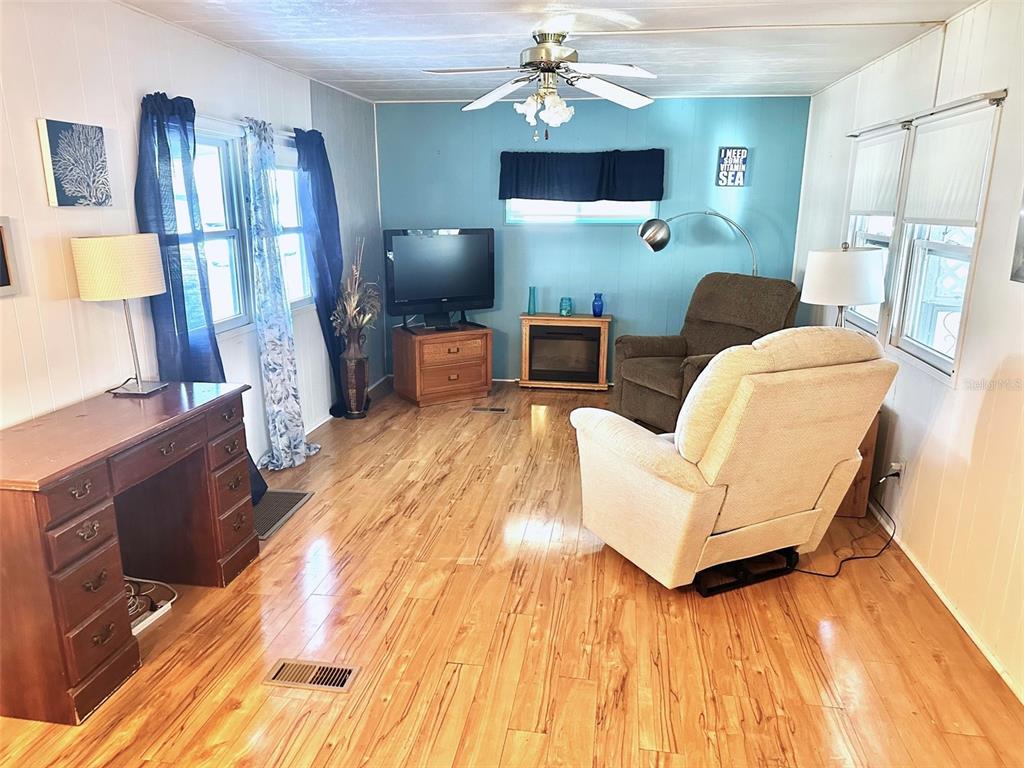 A living room features light wood flooring, a blue accent wall, and two recliner chairs — 9790 66TH STREET N UNIT 330, PINELLAS PARK, FL