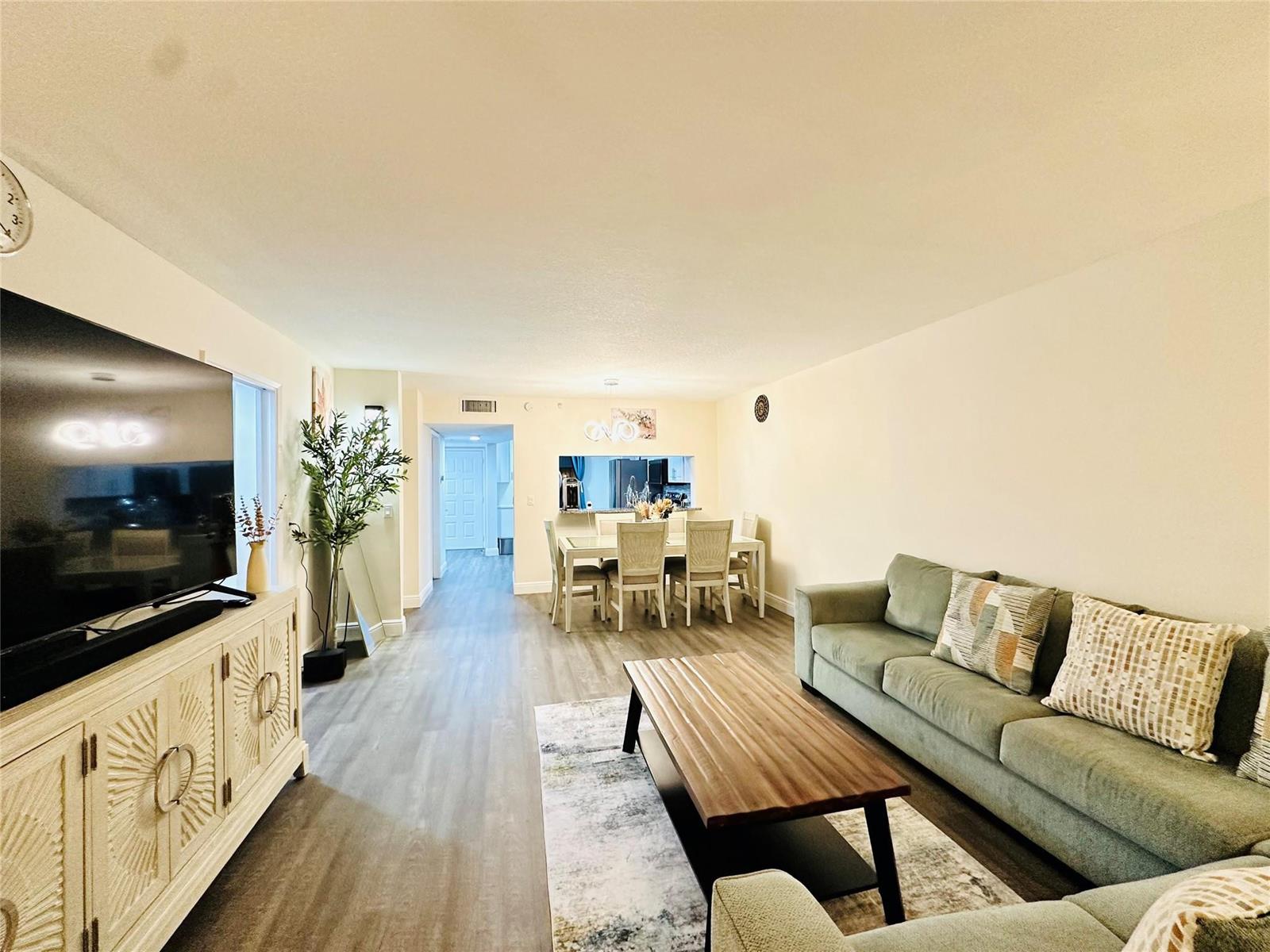 A living room with a green sofa, wood coffee table, and dining area in back — 2200 S Cypress Bend Drive # 802, Pompano Beach FL 33069, POMPANO BEACH, FL
