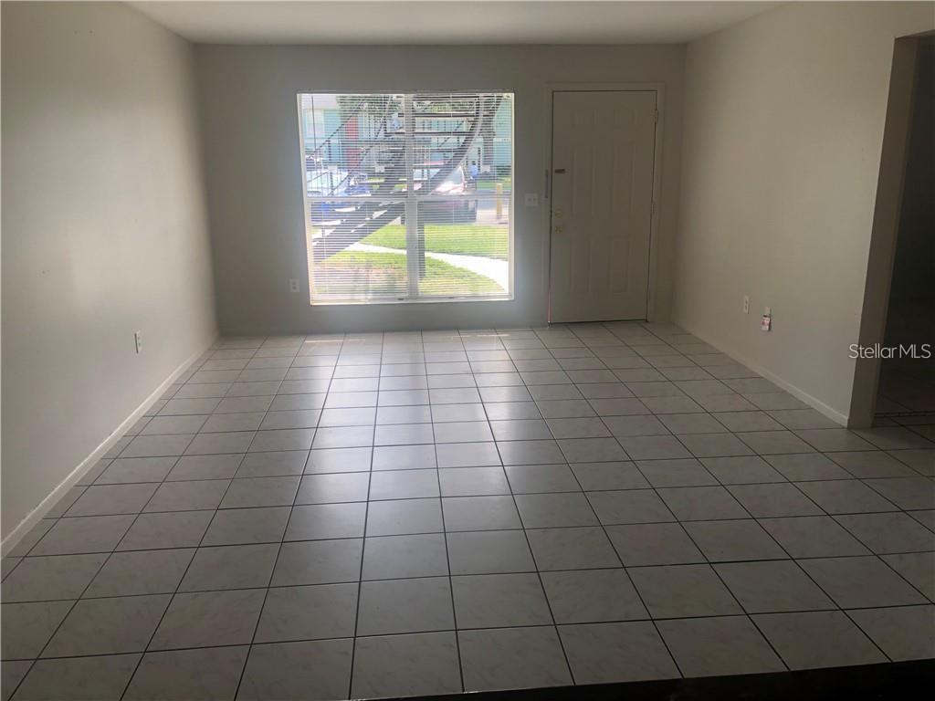 An empty room with white tile flooring, a large window, and an exterior door — 1896 CARALEE BOULEVARD UNIT 1, ORLANDO, FL