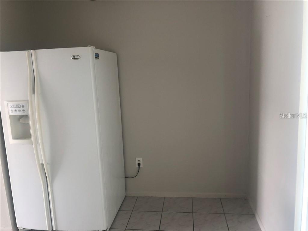 A white side-by-side refrigerator sits in a corner with light-colored tile flooring — 1896 CARALEE BOULEVARD UNIT 1, ORLANDO, FL