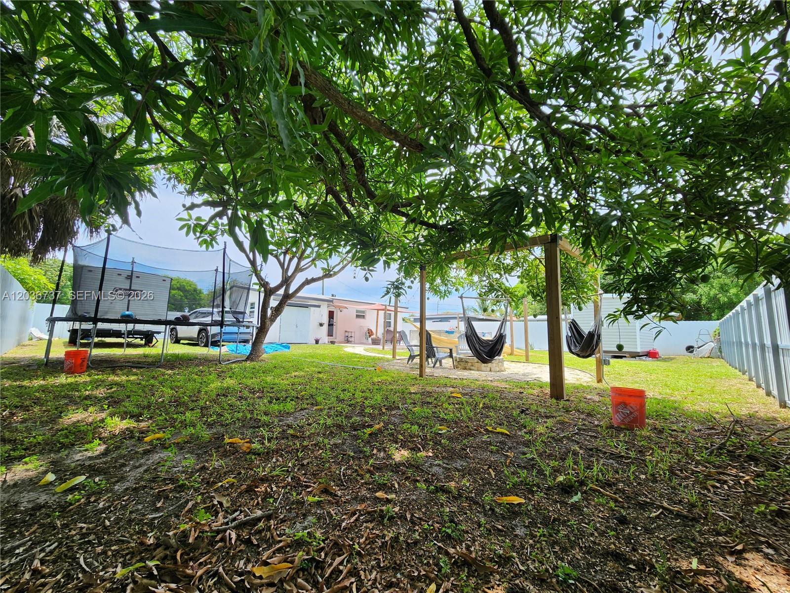 A backyard features a trampoline, a wooden swing frame with hammocks, and mature trees — 721 NW 33rd Ave, Lauderhill FL 33311, LAUDERHILL, FL