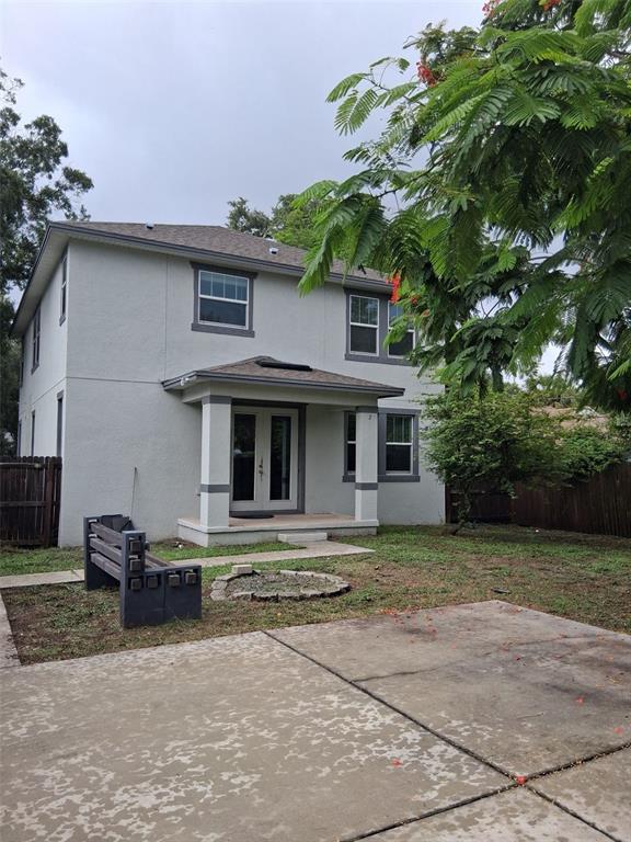 A two-story house exterior with a concrete patio, a fire pit, and a wooden bench — 2736 S 3RD AVENUE S, ST PETERSBURG, FL
