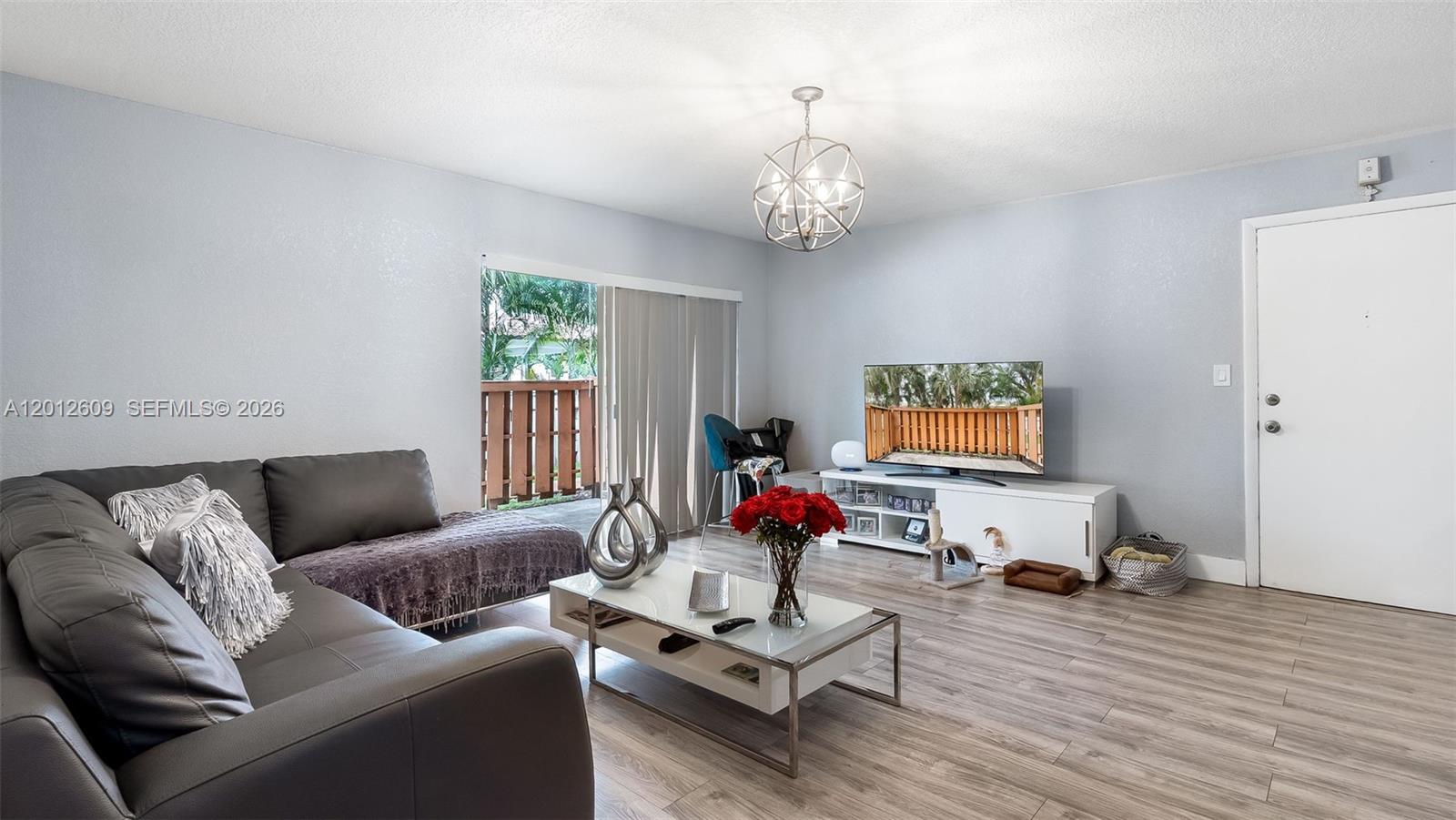 A living room features a grey sofa, white coffee table, television console, and sliding glass doors — 7208 Fairway Dr # I9, Miami Lakes FL 33014, MIAMI LAKES, FL