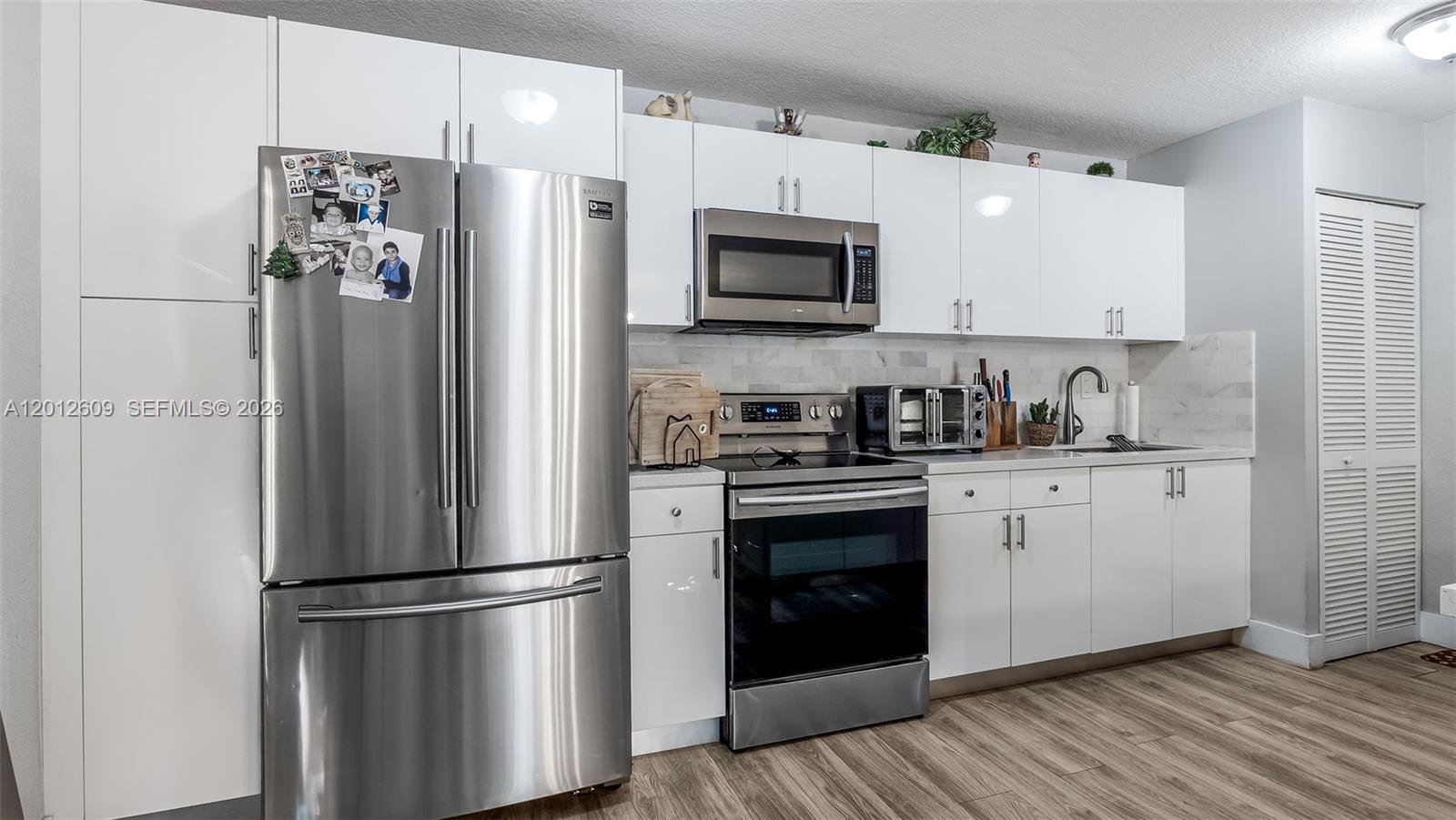 A modern kitchen features white cabinets, stainless steel appliances, and wood-look flooring — 7208 Fairway Dr # I9, Miami Lakes FL 33014, MIAMI LAKES, FL