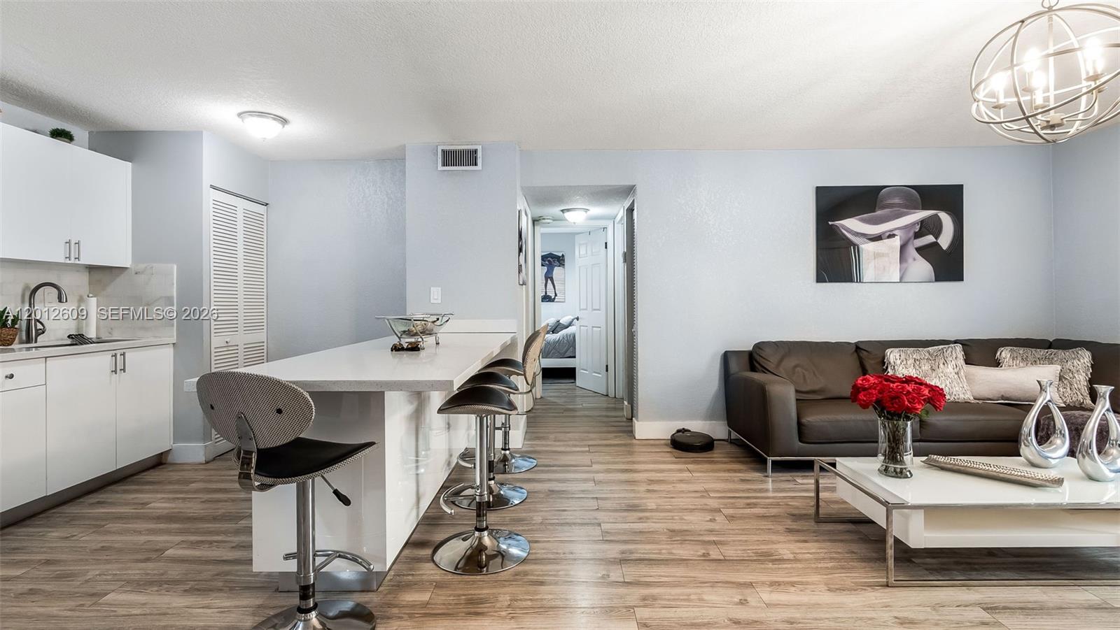 A kitchen with a white breakfast bar opens into a living room with a sofa — 7208 Fairway Dr # I9, Miami Lakes FL 33014, MIAMI LAKES, FL