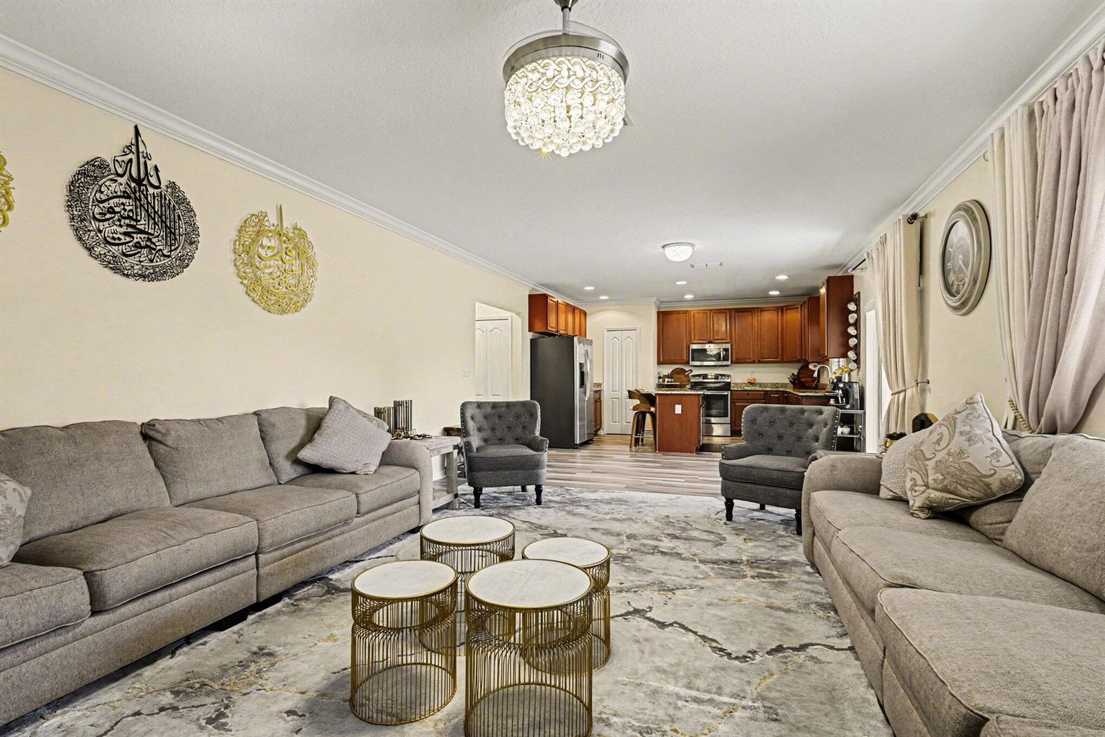 A living room with gray sofas, accent chairs, and a kitchen in the background — 1688 Attilburgh Boulevard, West Melbourne FL 32904, WEST MELBOURNE, FL