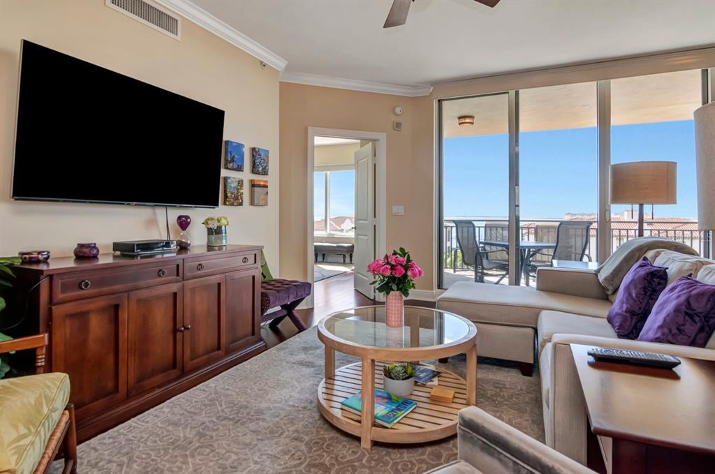 A living room features a large television, wooden media console, sectional sofa, and balcony access — 5823 BOWEN DANIEL DRIVE UNIT 604, TAMPA, FL