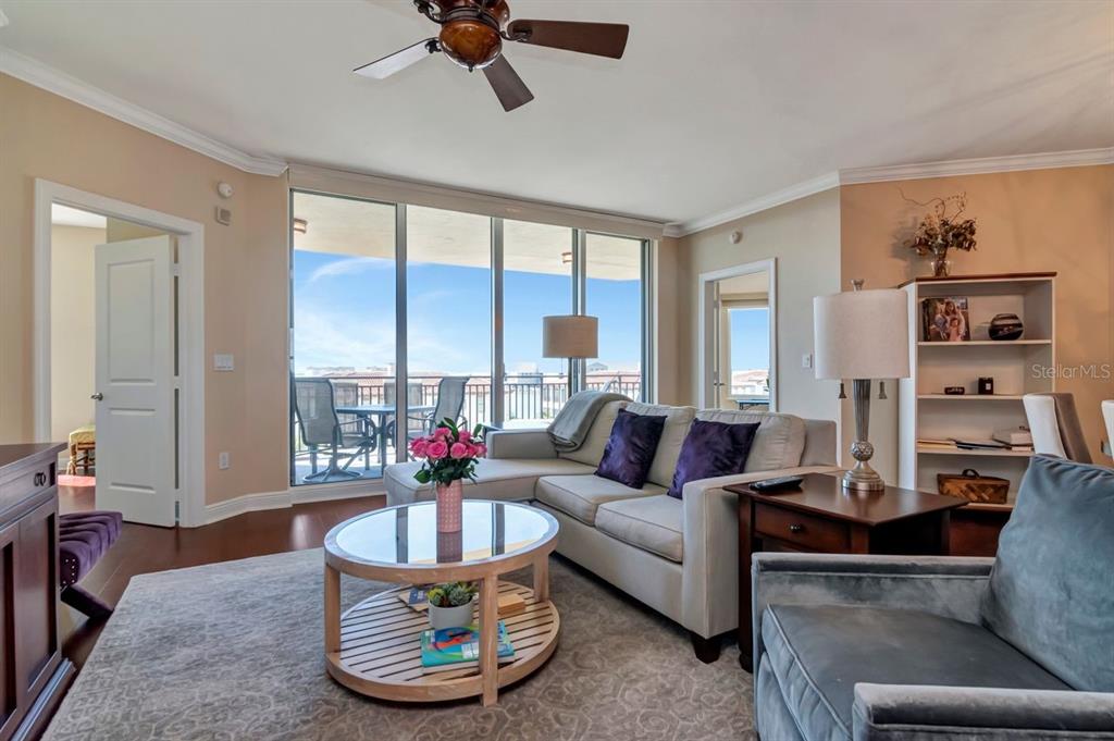 A living room features a sectional sofa, a round coffee table, and floor-to-ceiling balcony windows — 5823 BOWEN DANIEL DRIVE UNIT 604, TAMPA, FL