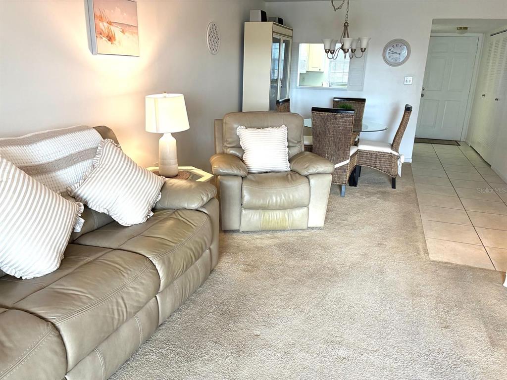 A living room features a beige leather sofa, a matching recliner, and a dining area — 4703 1ST COURT W UNIT 393, BRADENTON, FL