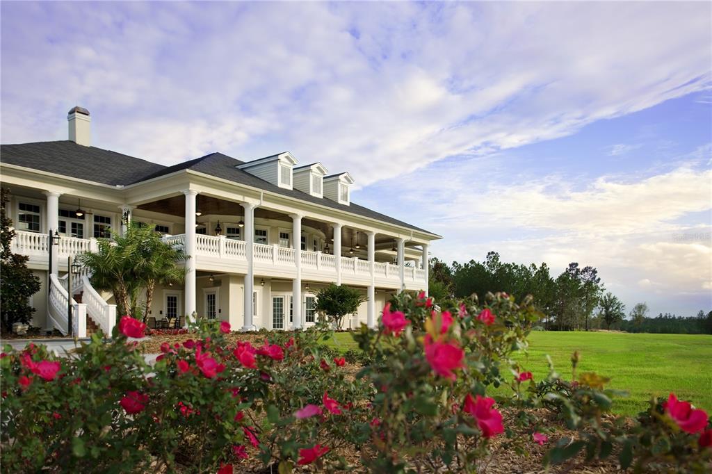 A large, two-story white house with a wrap-around porch and dormer windows overlooks a garden — 5368 GRAND SUMMIT DRIVE, BROOKSVILLE, FL