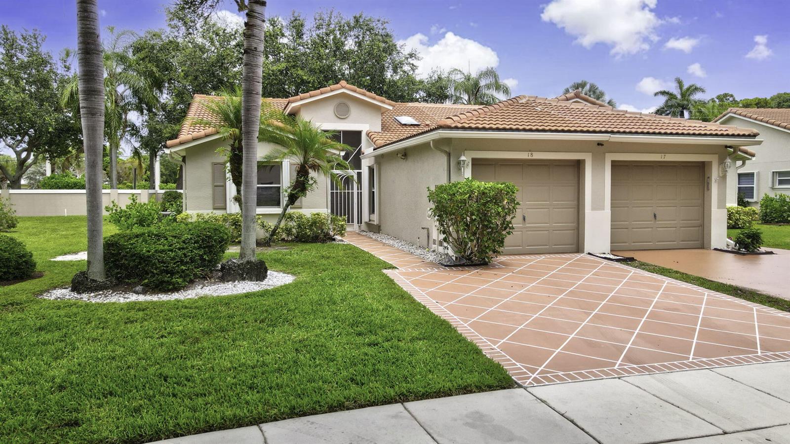 A single-story house with a tiled roof, two garage doors, and a patterned concrete driveway — 18 Sausalito Drive, Boynton Beach FL 33436, BOYNTON BEACH, FL