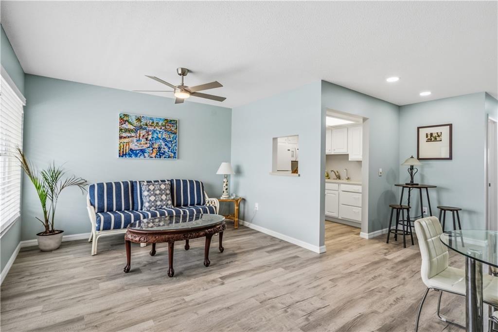 A living room with light blue walls, wood-look flooring, a striped sofa, and a ceiling fan — VERO BEACH, FL