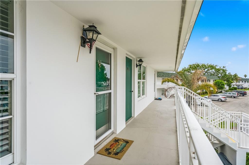 An outdoor balcony with white railings, a green door, and a welcome mat — VERO BEACH, FL