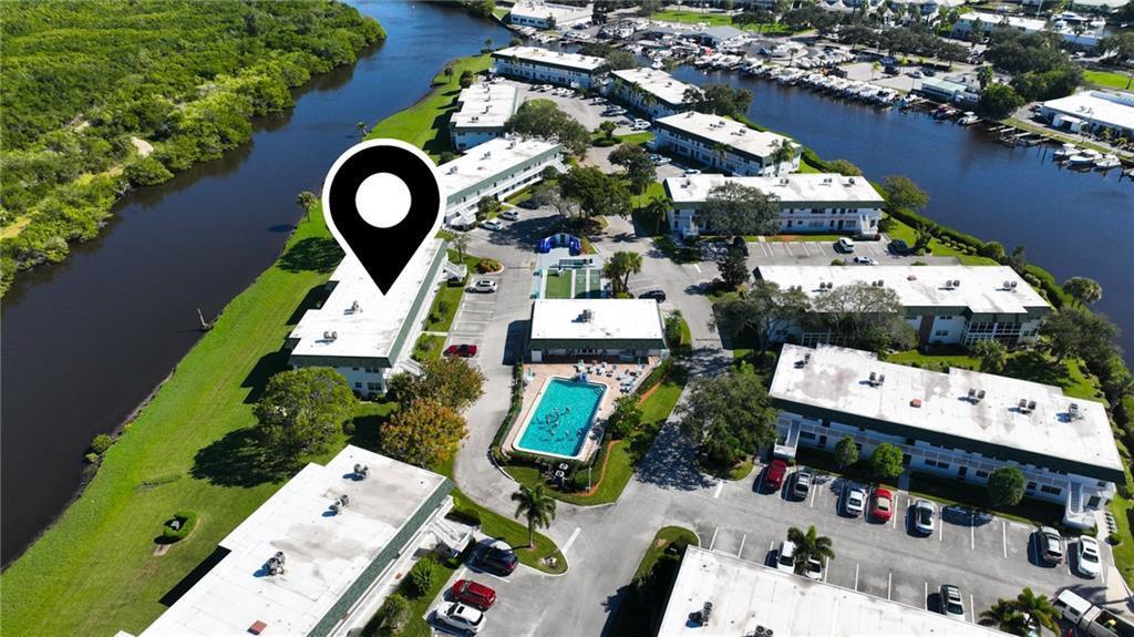 An aerial view shows a multi-building apartment complex with a swimming pool and canal — VERO BEACH, FL