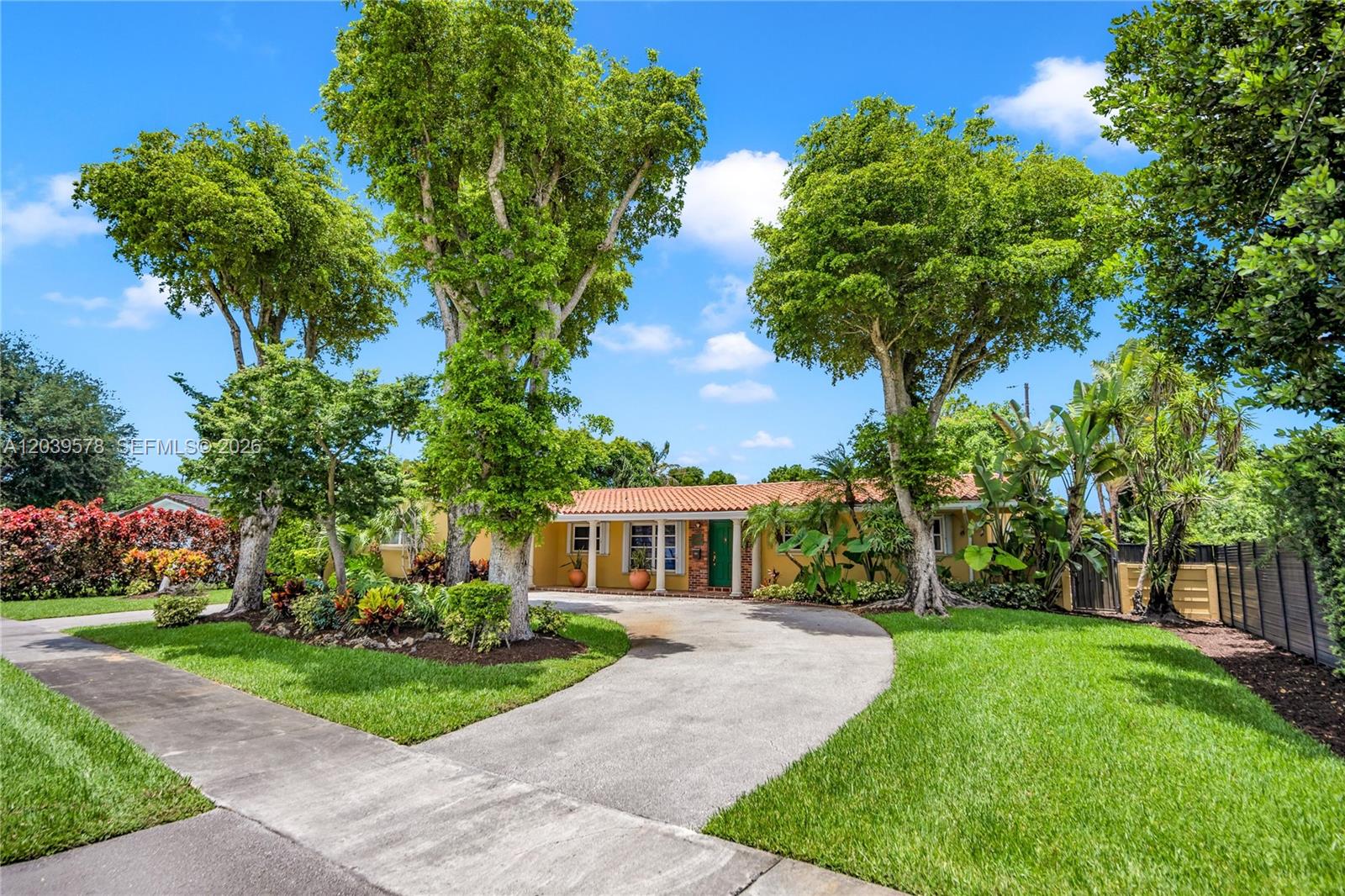 A yellow single-story house with a tile roof and a curved driveway sits behind trees — 8701 SW 87th Ct, Miami FL 33173, MIAMI, FL