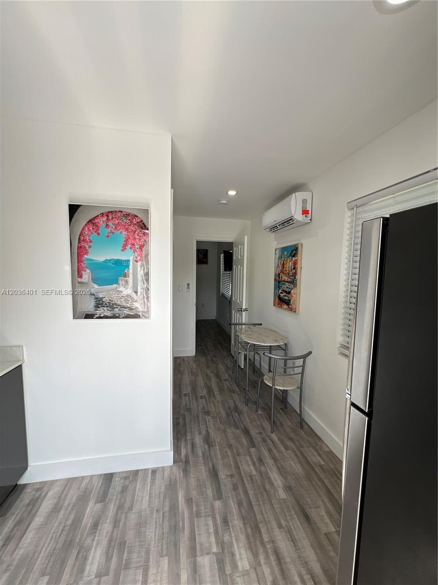 A small kitchen area features wood-look flooring, a dining set, and a wall-mounted air conditioner — 2847 Polk St # 3, Hollywood FL 33020, HOLLYWOOD, FL