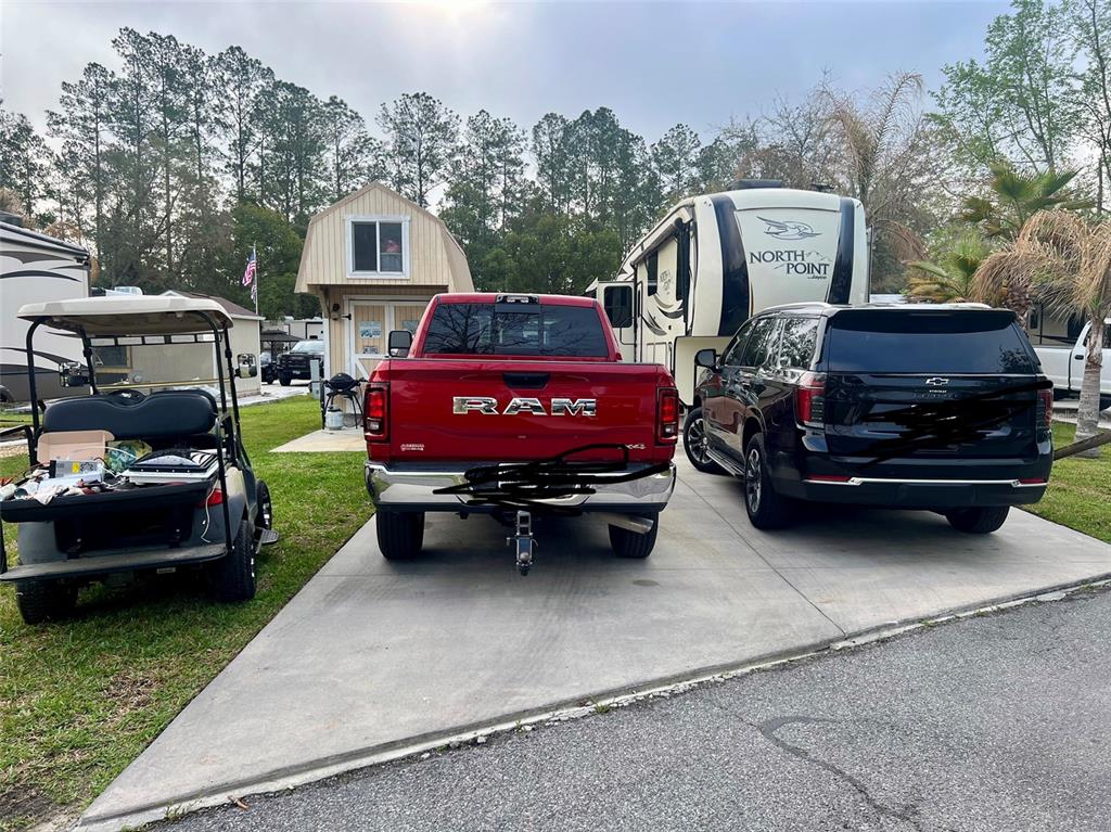 A red pickup truck, a black SUV, and a golf cart are parked on a driveway — 2905 NE 104TH AVENUE UNIT 99, SILVER SPRINGS, FL