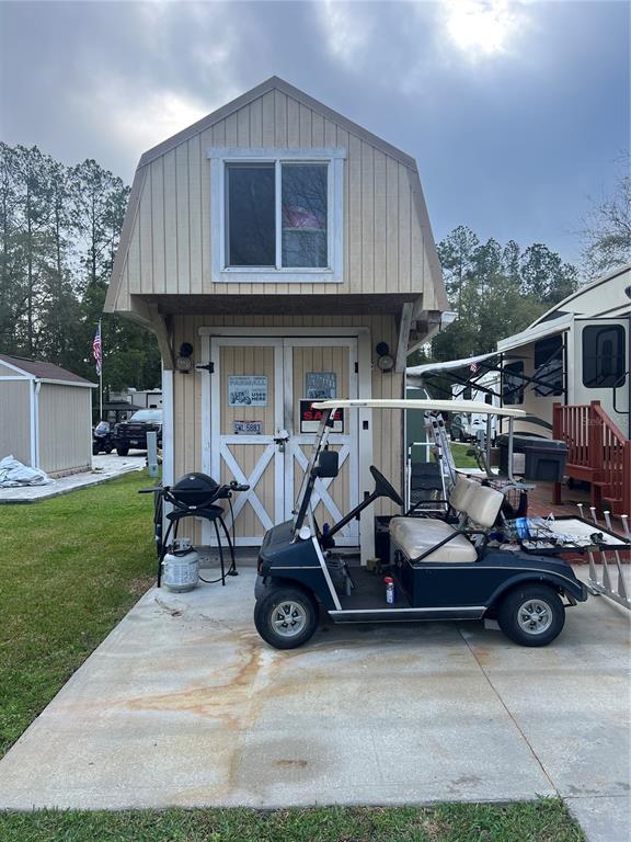 A two-story shed with a golf cart parked on a concrete pad in front — 2905 NE 104TH AVENUE UNIT 99, SILVER SPRINGS, FL