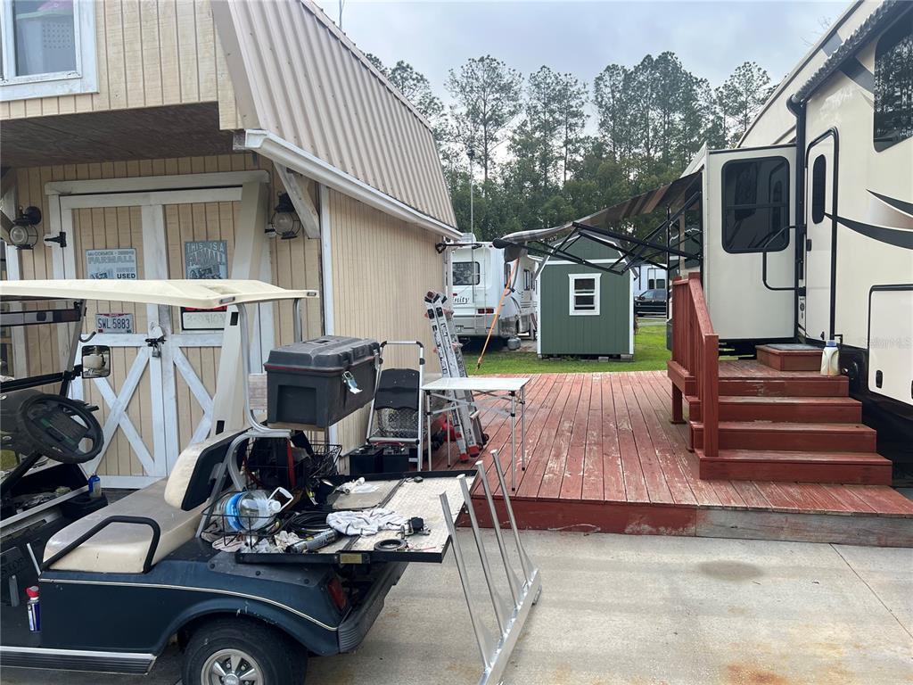 A golf cart sits on a concrete driveway in front of a shed and RV — 2905 NE 104TH AVENUE UNIT 99, SILVER SPRINGS, FL