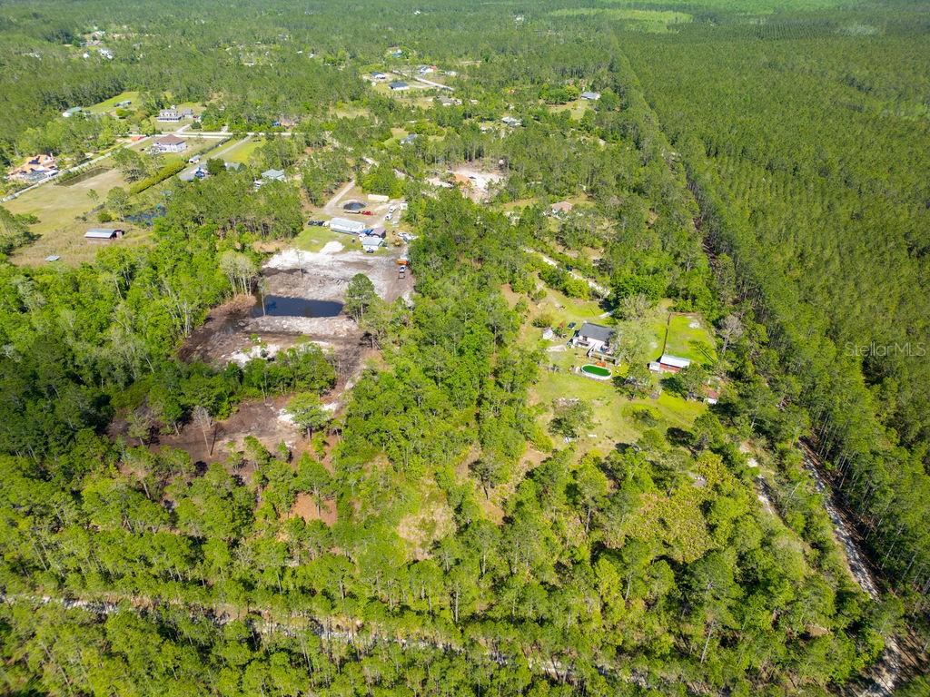 An aerial view shows a rural residential property with scattered houses, wooded areas, and ponds — 3770 BALSAM COURT, ORMOND BEACH, FL