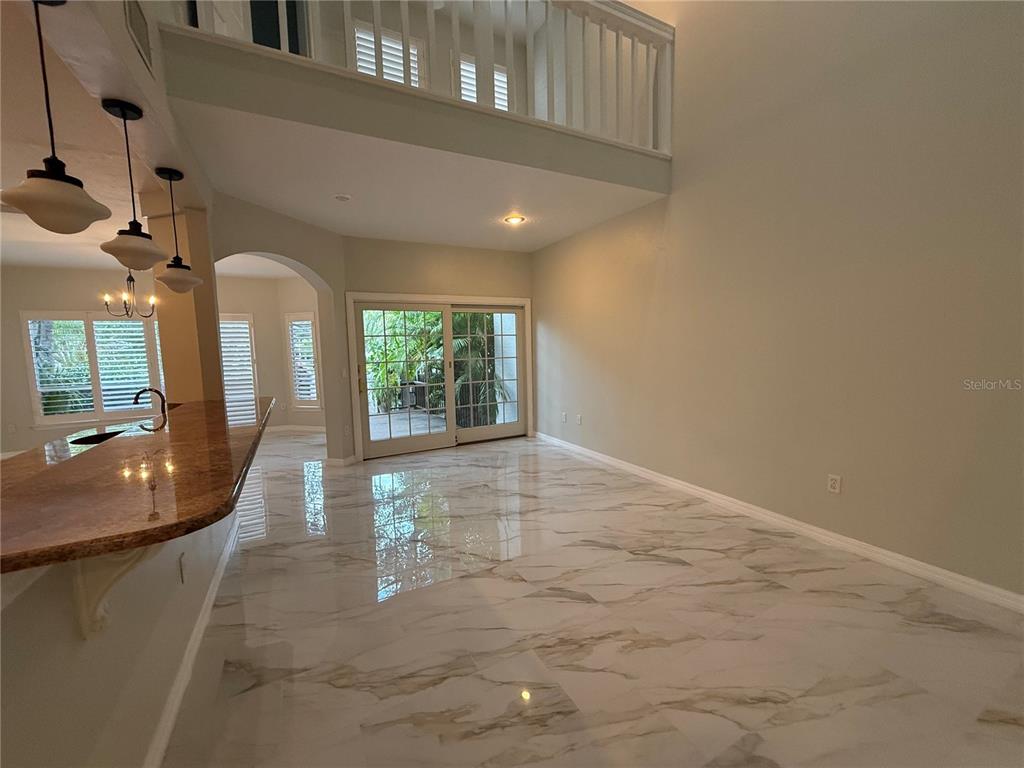 A bright living area features white marble-look tile flooring, a high ceiling, and sliding glass doors — 1195 SHIPWATCH CIRCLE, TAMPA, FL