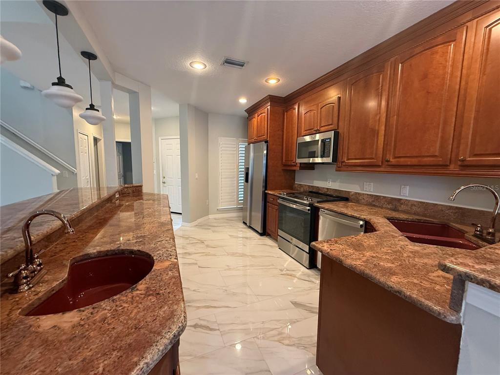A kitchen features wood cabinets, granite countertops, stainless steel appliances, and white tile flooring — 1195 SHIPWATCH CIRCLE, TAMPA, FL