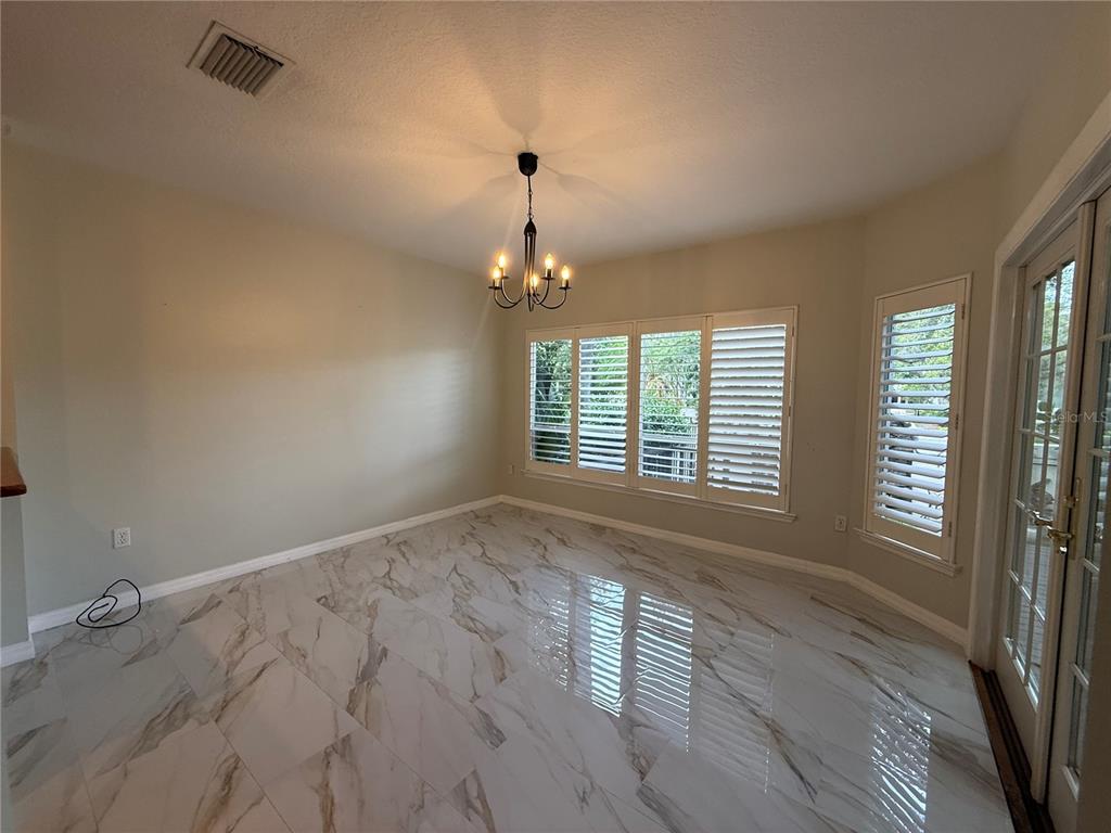 A dining room with white marble-look tile flooring, a chandelier, and plantation shutters on windows — 1195 SHIPWATCH CIRCLE, TAMPA, FL