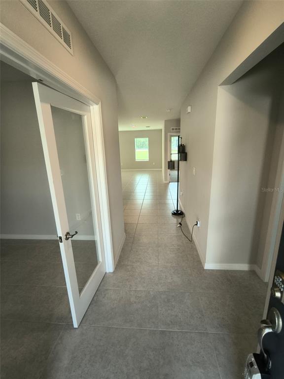 A tiled entryway leads to a hallway with a glass-paneled door and a distant window — 45 WELLWOOD LANE, PALM COAST, FL