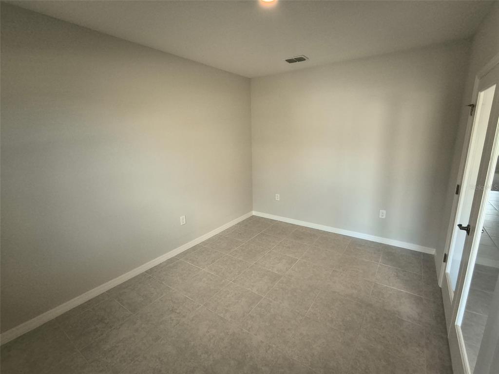 An empty room with light gray walls, tile flooring, and a glass-paneled door — 45 WELLWOOD LANE, PALM COAST, FL