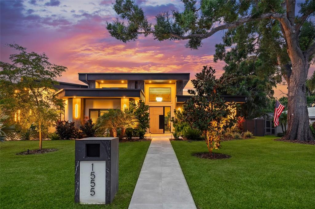 A modern house with a flat roof, stone mailbox, and landscaped lawn at sunset — 1555 EASTBROOK DRIVE, SARASOTA, FL