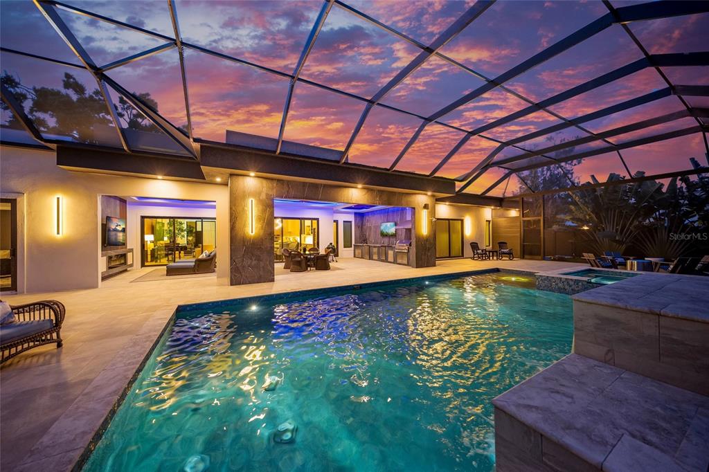 A covered patio with a swimming pool and spa under a sunset sky — 1555 EASTBROOK DRIVE, SARASOTA, FL