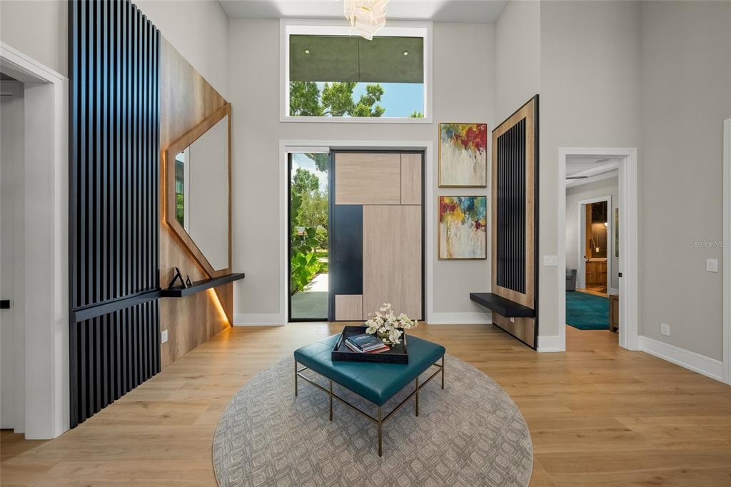 A modern entryway features a geometric front door, wood-slat wall accents, and a teal ottoman — 1555 EASTBROOK DRIVE, SARASOTA, FL