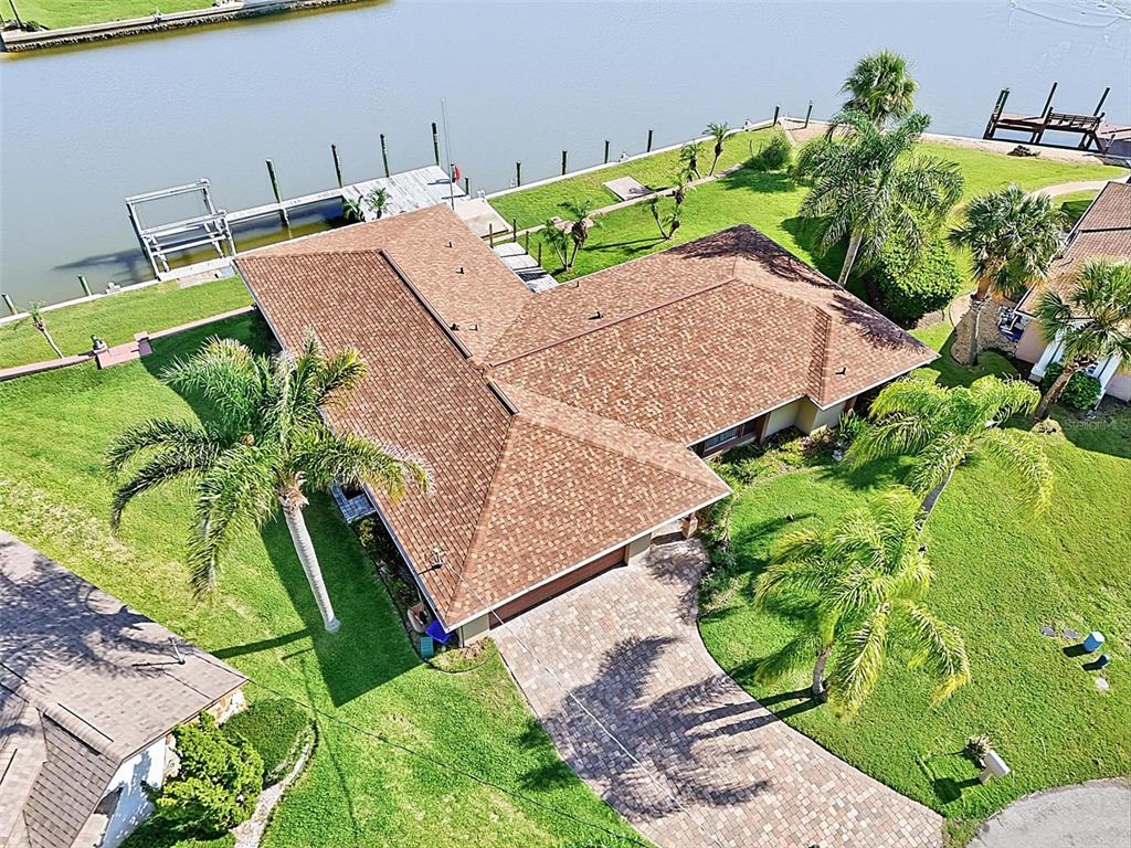 An aerial view of a waterfront house with a brown shingled roof and palm trees — 10 CROW COURT, PALM COAST, FL