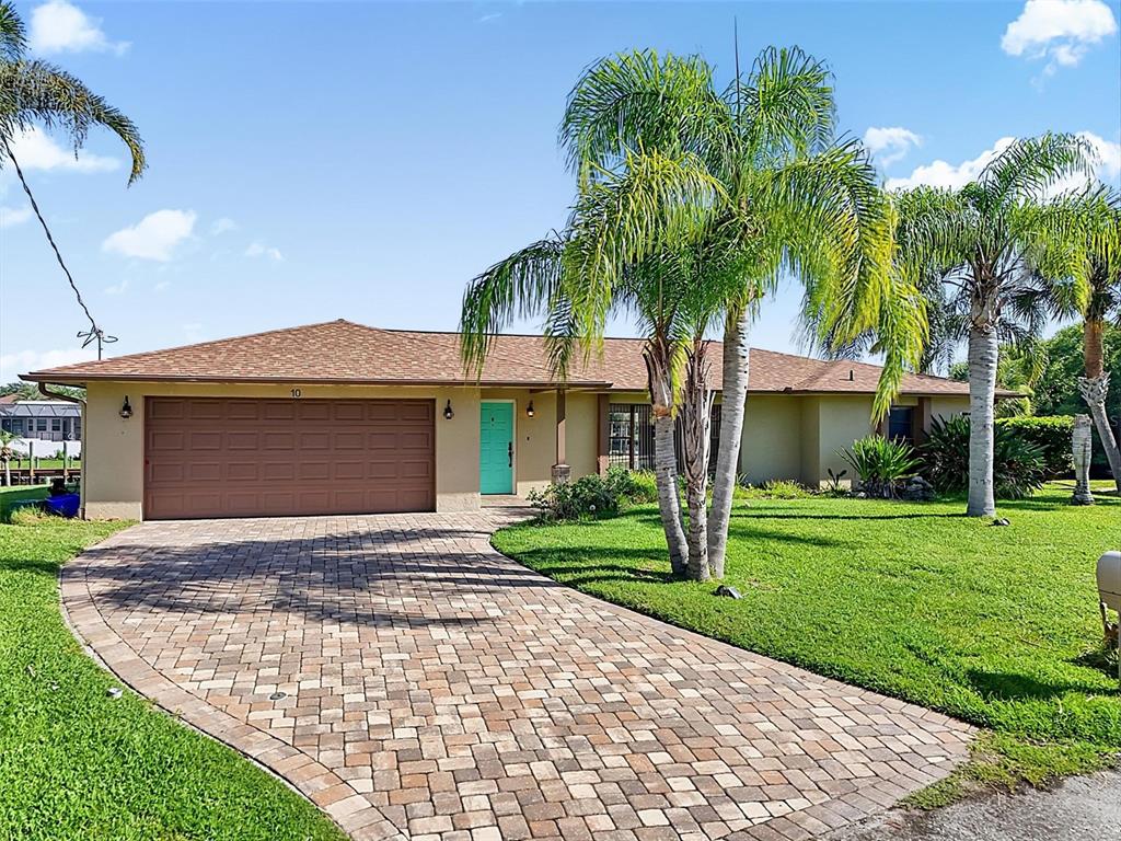 A single-story house with a brown roof, a turquoise front door, and a paver driveway — 10 CROW COURT, PALM COAST, FL