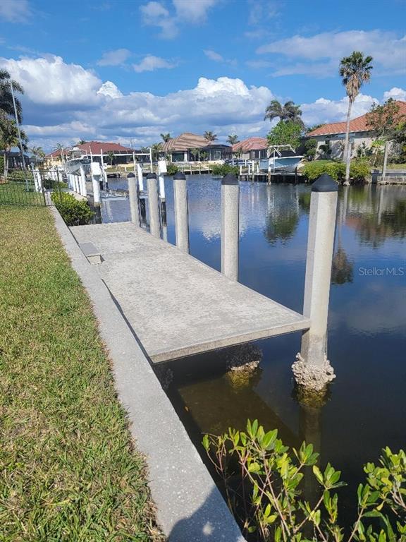 A concrete boat dock extends over a canal with several pilings and nearby residential homes — 5038 BAL HARBOR BOULEVARD, PUNTA GORDA, FL