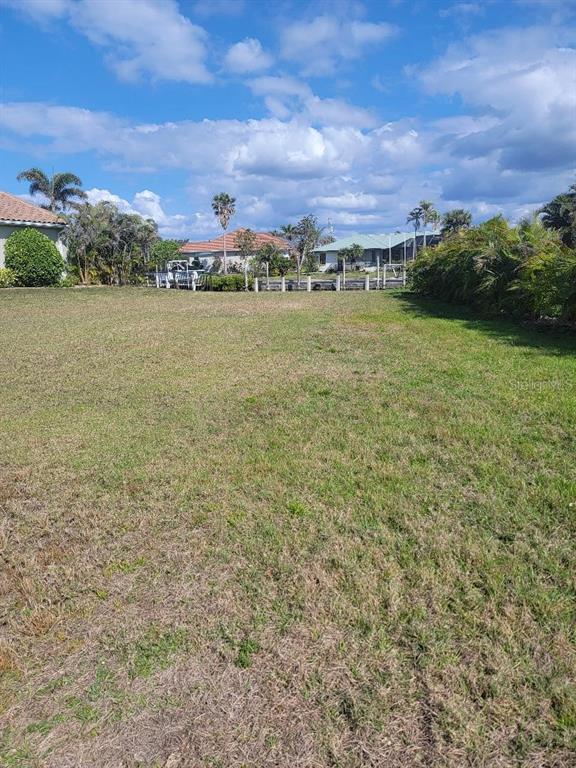 A grassy vacant lot features a canal view with neighboring houses in the background — 5038 BAL HARBOR BOULEVARD, PUNTA GORDA, FL
