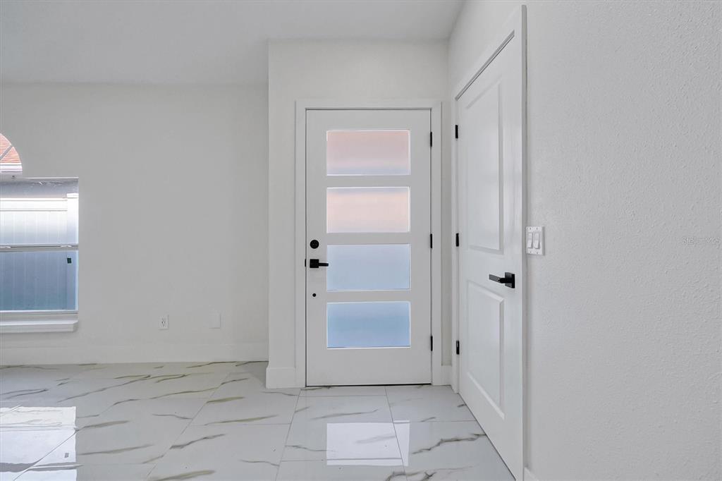 An entryway features white walls, marble-look tile flooring, a modern front door, and a closet — 2455 PARSONS POND CIRCLE, KISSIMMEE, FL