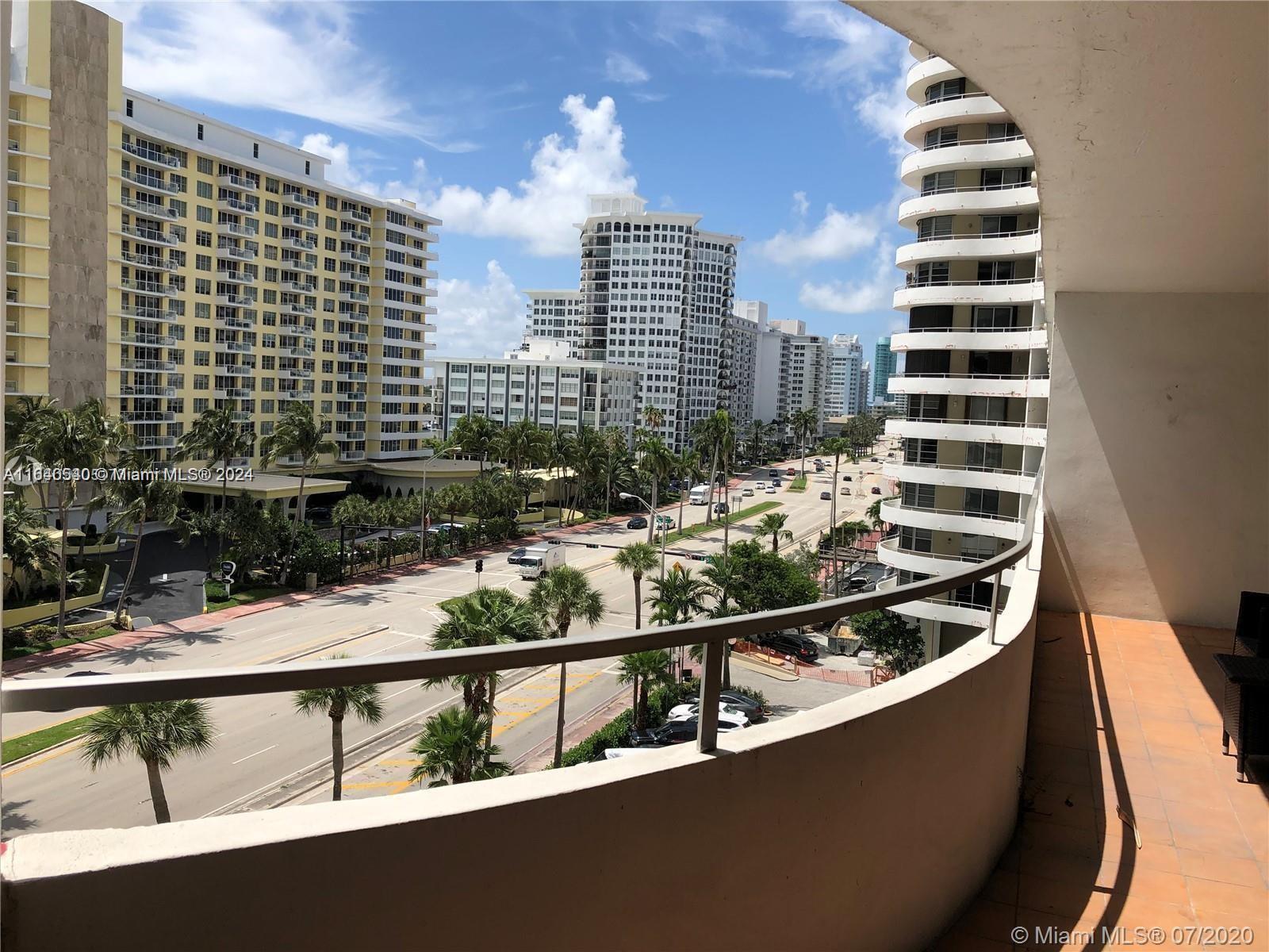 A balcony overlooks a multi-lane city street lined with palm trees and high-rise buildings — 5555 Collins Ave # 7T, Miami Beach FL 33140, MIAMI BEACH, FL
