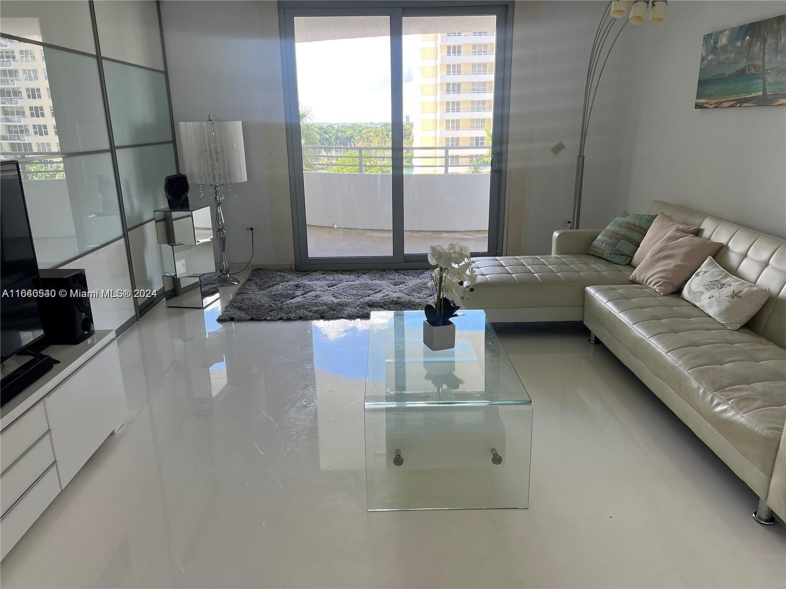 A living room features a white leather sectional, glass coffee table, and balcony access — 5555 Collins Ave # 7T, Miami Beach FL 33140, MIAMI BEACH, FL
